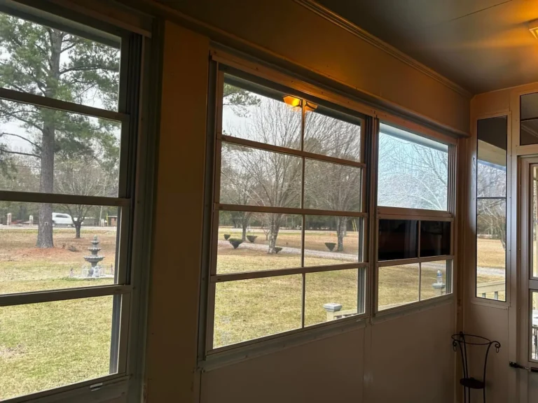 Enclosed sunroom with grid windows overlooking landscaped country acreage by Tiger Town Construction