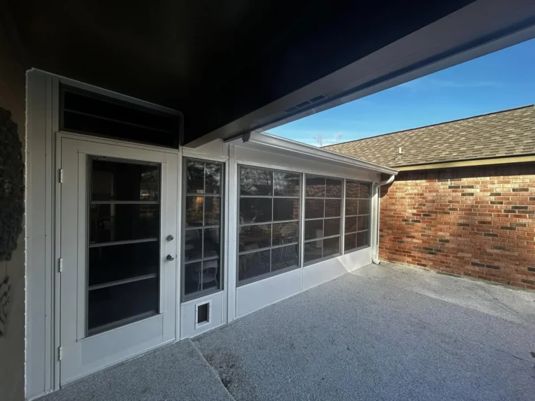 Glass sunroom exterior with grid windows and a French door on a brick home, built by Tiger Town Construction