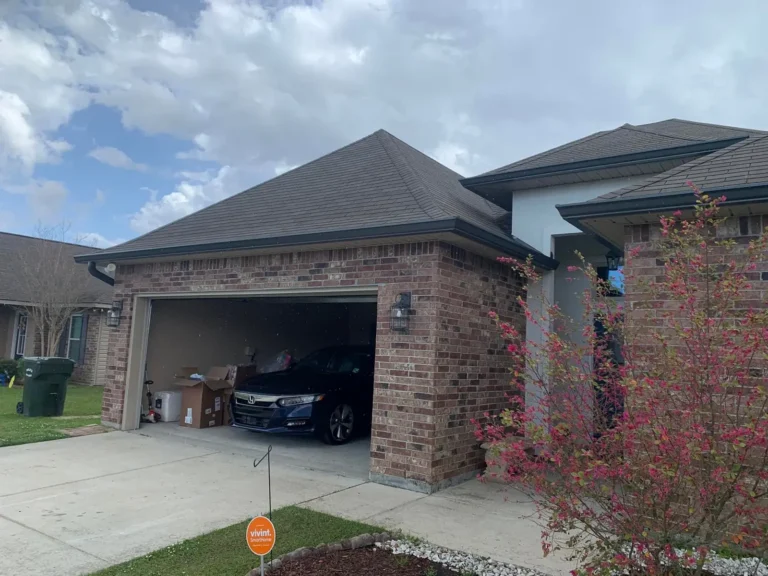 Seamless gutter along a brick home garage with hip roof and coach light, by Tiger Town Construction